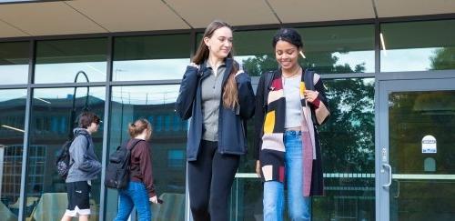 Two students walking outside Gaige Hall